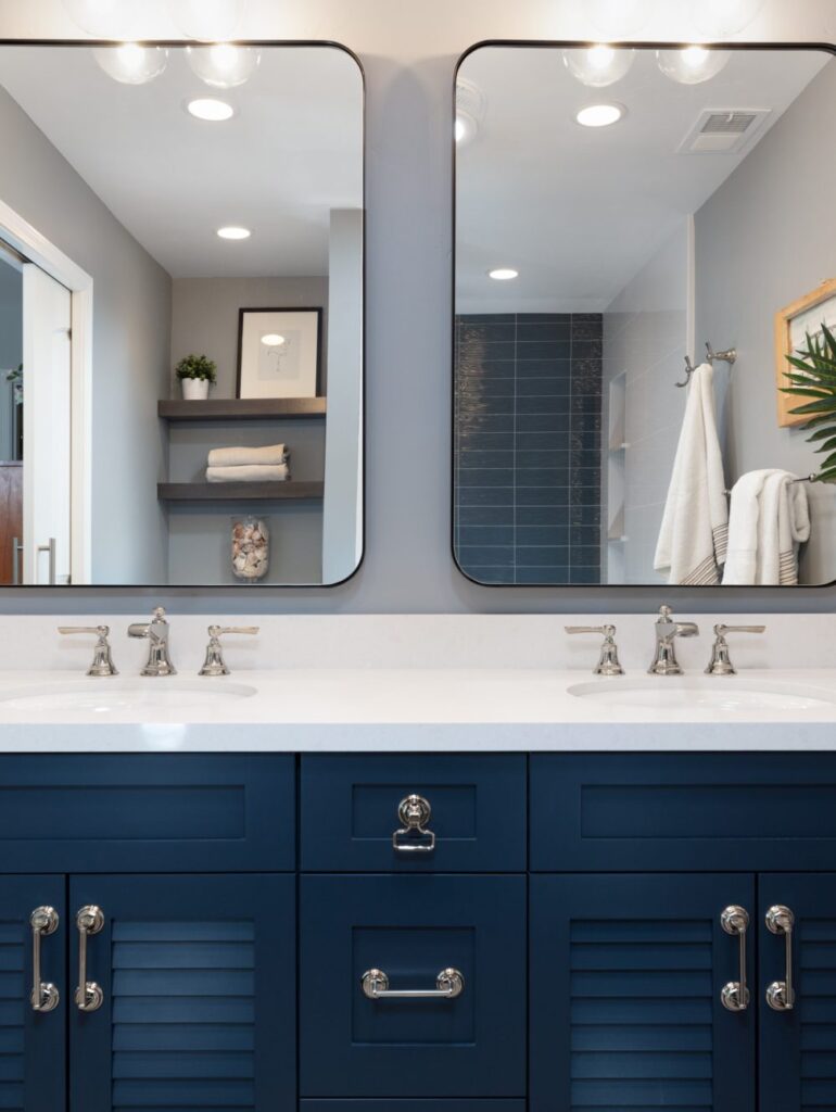 Bathroom featuring dark blue vanity with double sinks and mirrors