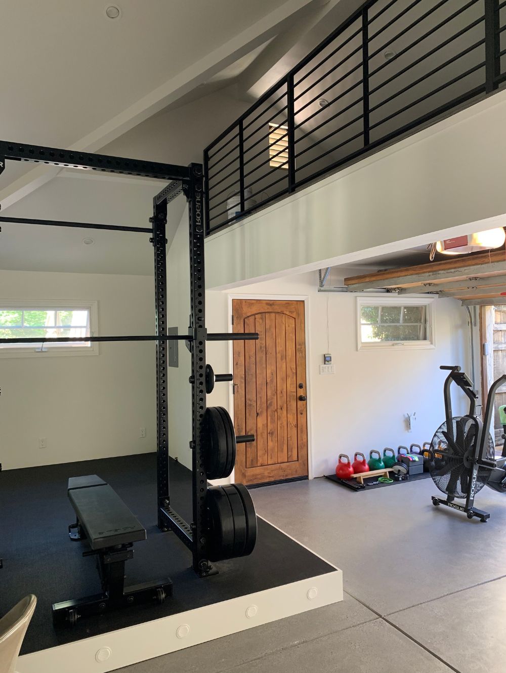 Weight lifting area, exercise bike and many kettlebells in a remodeled garage