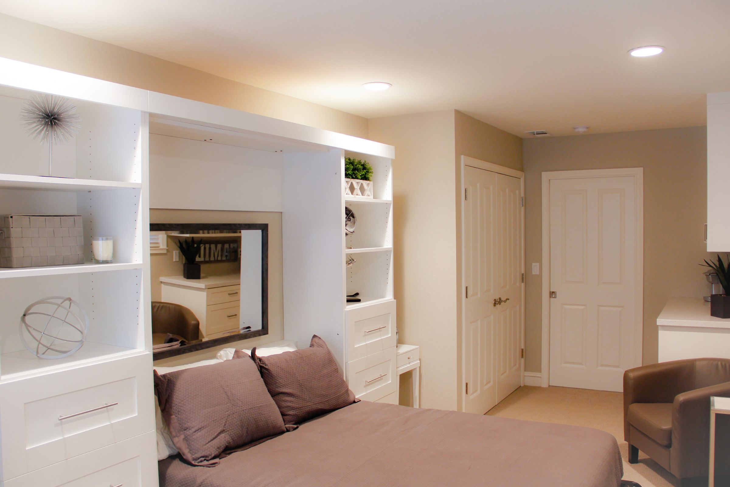Updated space with small desk and a large built-in shelving unit that includes a Murphy bed