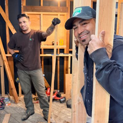 Two Gridley employees smiling while building frame of room